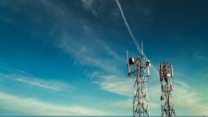 Cell tower in front of lightly cloudy blue sky