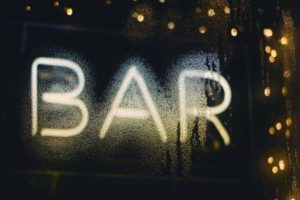 A neon light sign advertising a bar.